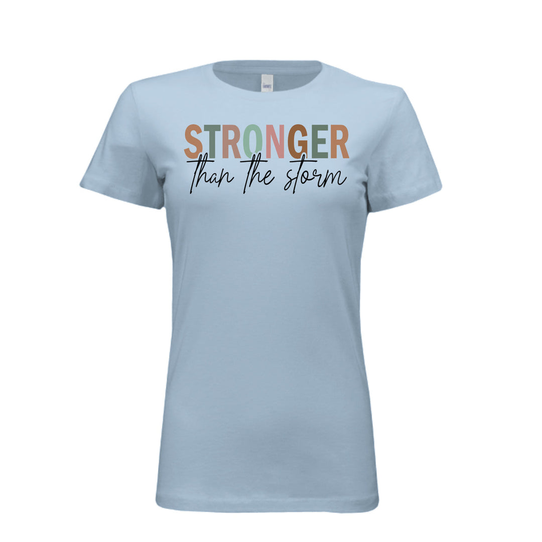 Women's fitted tee in baby blue with bold multi-color “STRONGER” and black script “than the storm” across the chest.